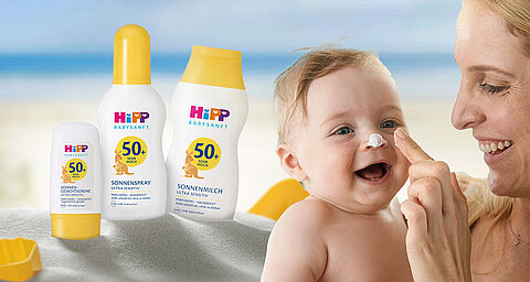 Ein Baby, das mit der Hand einer Frau Sonnenschutzmittel aufträgt, begleitet von verschiedenen Sonnenschutzmitteln mit LSF-Werten.