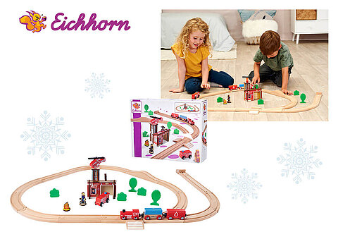 Kinder spielen mit einer Holzeisenbahn, und die Schachtel mit dem Spielzeug ist ausgestellt.