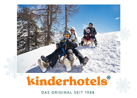 Eine vierköpfige Familie schlittelt einen verschneiten Hügel hinunter.