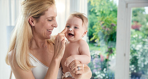 Ein zärtlicher Moment zwischen einer Mutter und ihrem Baby, in dem die Mutter spielerisch die Nase des Babys berührt.