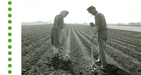 Zwei Personen sind mit landwirtschaftlichen Arbeiten auf einem gepflügten Feld beschäftigt.