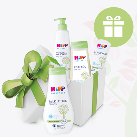 Ein Set von Babypflegeprodukten in einer weißen Schachtel, begleitet von einer grünen Schleife und einem Geschenksymbol.