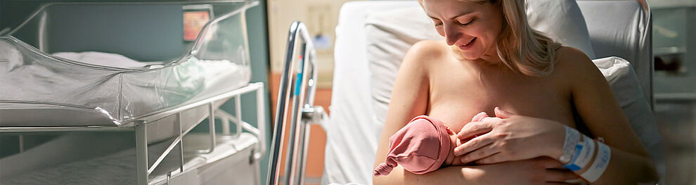 Ein zärtlicher Moment zwischen einer Mutter und ihrem neugeborenen Baby in einem Krankenhaus.