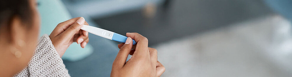 Eine Person hält einen Ovulationstest in der Hand.