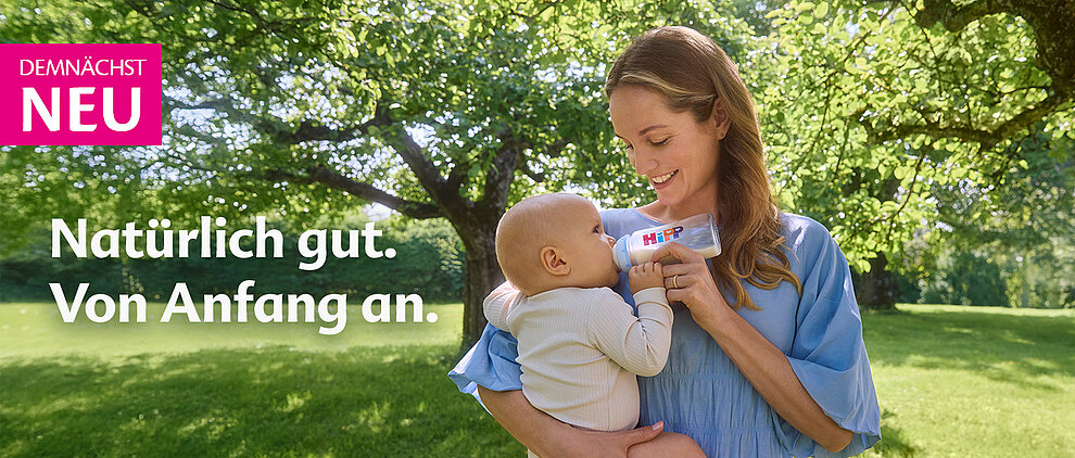 Eine Frau füttert ein Baby im Freien.