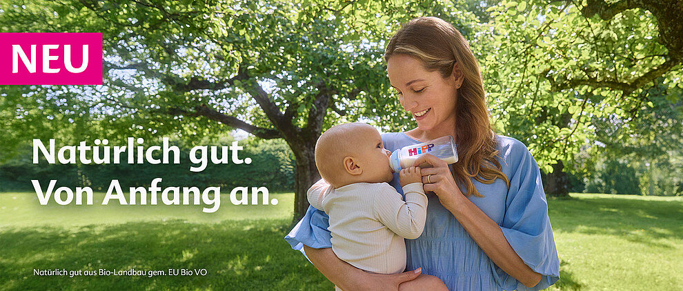 Eine Frau füttert ein Baby im Freien.