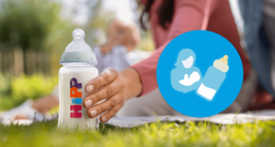 Eine Mutter sitzt mit ihrem Baby auf einer Wiese und hält ein HiPP Fläschchen 