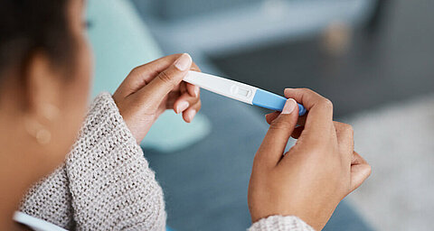 Eine Person hält einen Schwangerschaftstest in der Hand.