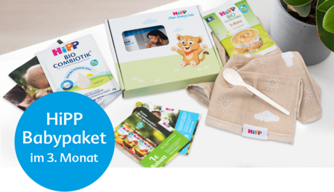 Eine Werbebox von 'BabyClub' mit einer grünen Faltflasche, einer 'Bio Combiotik'-Packung und einer Blattpflanze in einem Korb.