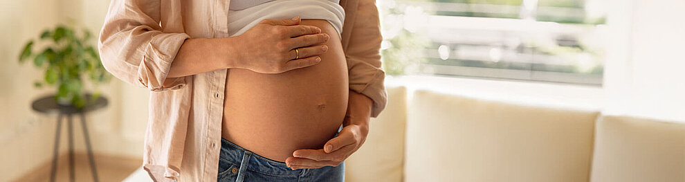 Eine Person, die schwanger ist, berührt sanft ihren Bauch.