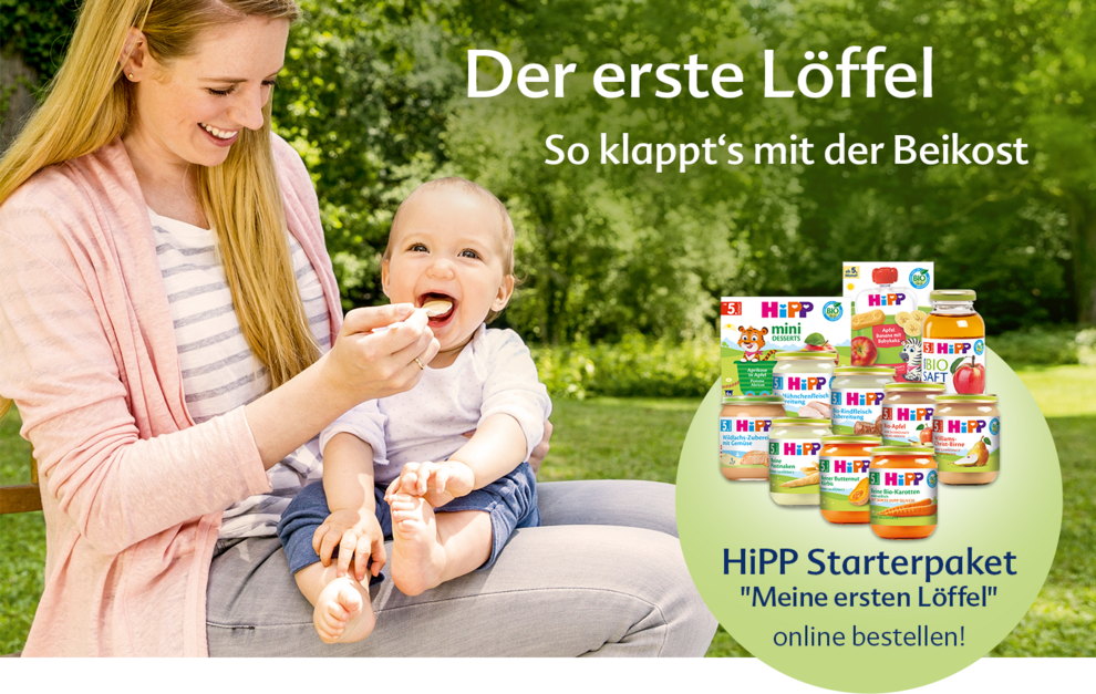 Eine Mutter füttert ihr Baby mit einem Löffel, während ein Werbebanner für das "HiPP Starterpaket" für Babynahrung wirbt.