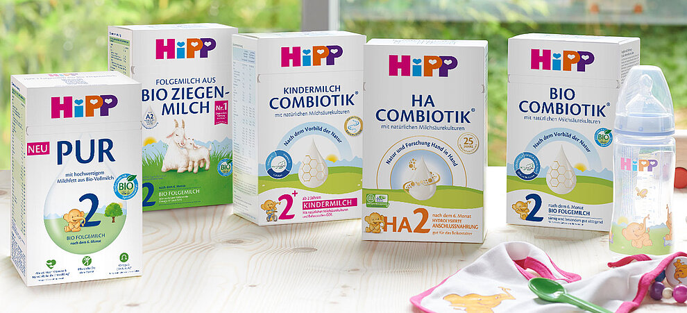 Eine Reihe von Säuglingsmilchprodukten der Marke "HiPP", darunter "BIO ZIEGEN-MILCH", "KINDERMILCH", "HA COMBIOTIK" und "BIO FOLGEMILCH". Jedes Produkt ist mit seinem Entwicklungsstadium, seinem Nährstoffgehalt und seinen Inhaltsstoffen gekennzeichnet.