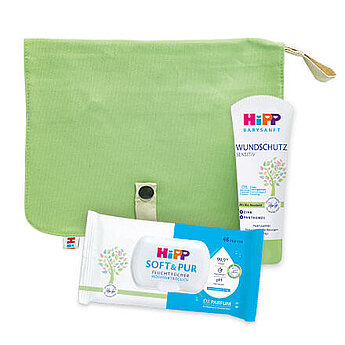 Ein grüner Beutel mit einem Babytuch, einer Babylotion und einem Spender für Babytücher.