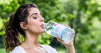 Schwangere Frau beim Trinken von HiPP Baby Quellwasser 4. Schwangerschaftsmonat