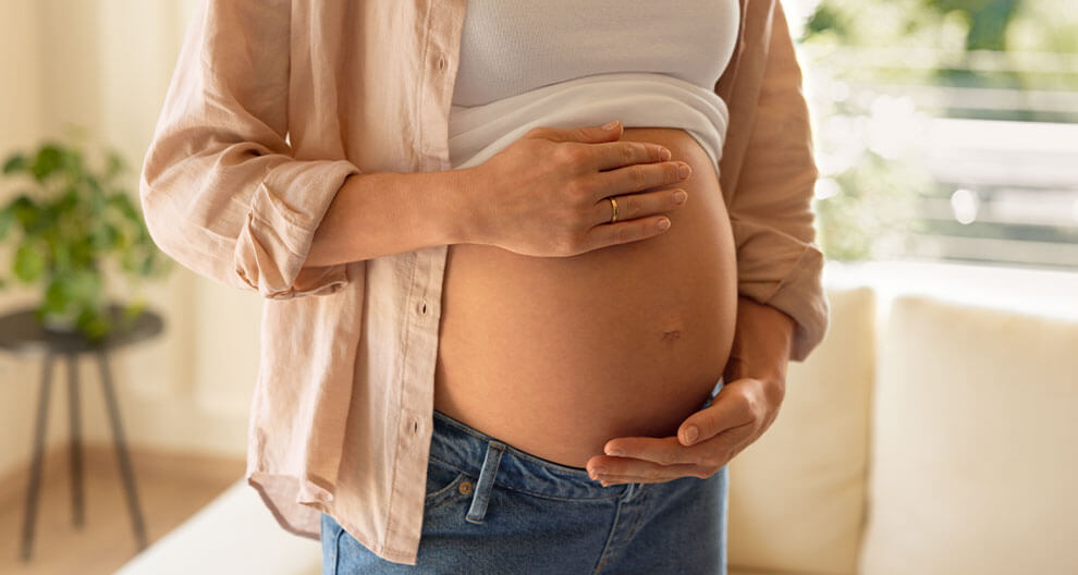 Eine Person, die schwanger ist, berührt sanft ihren Bauch.