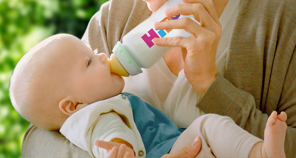 Ein freudiger Familienmoment, in dem eine Frau ihr Baby mit der Flasche füttert, während ein Mann liebevoll zuschaut.