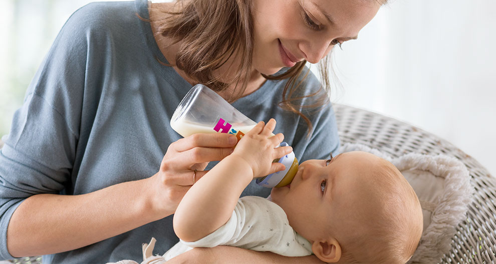 Ein Baby, das von einer Frau mit der Flasche gefüttert wird.